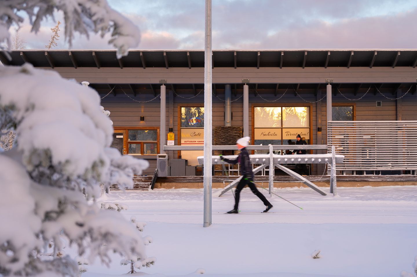 Hiihtäjä kulkee ladulla Uuttusuon kahvilan edestä talvipäivänä.